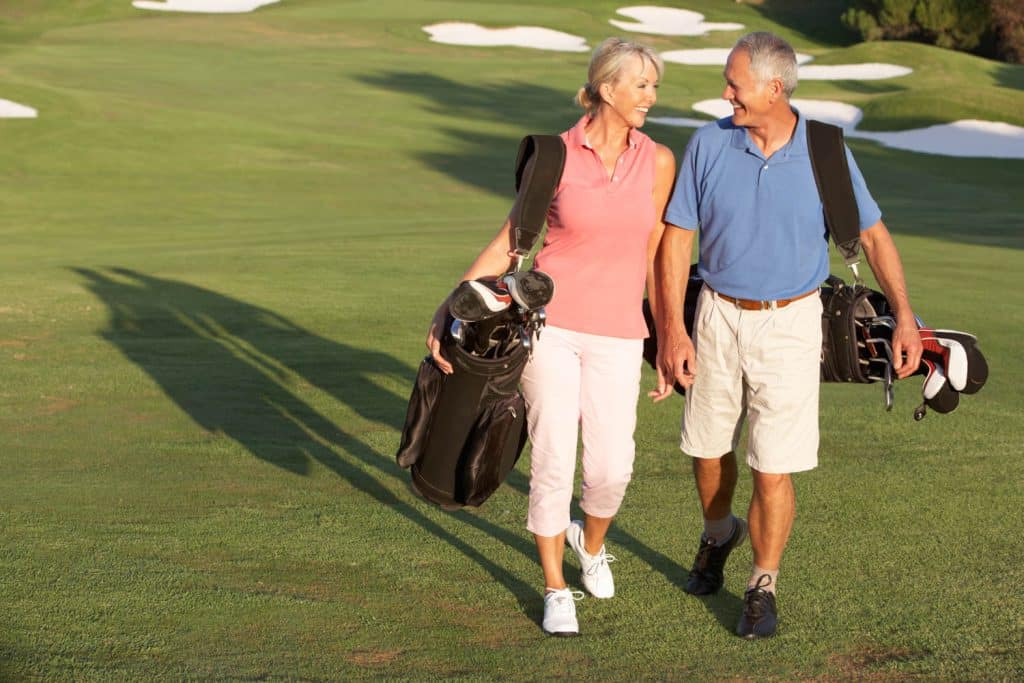 Senior Couple Walking Along Golf Course Carrying Bagsnear Sierra Sol Mobile Homes For Sale Sparks
